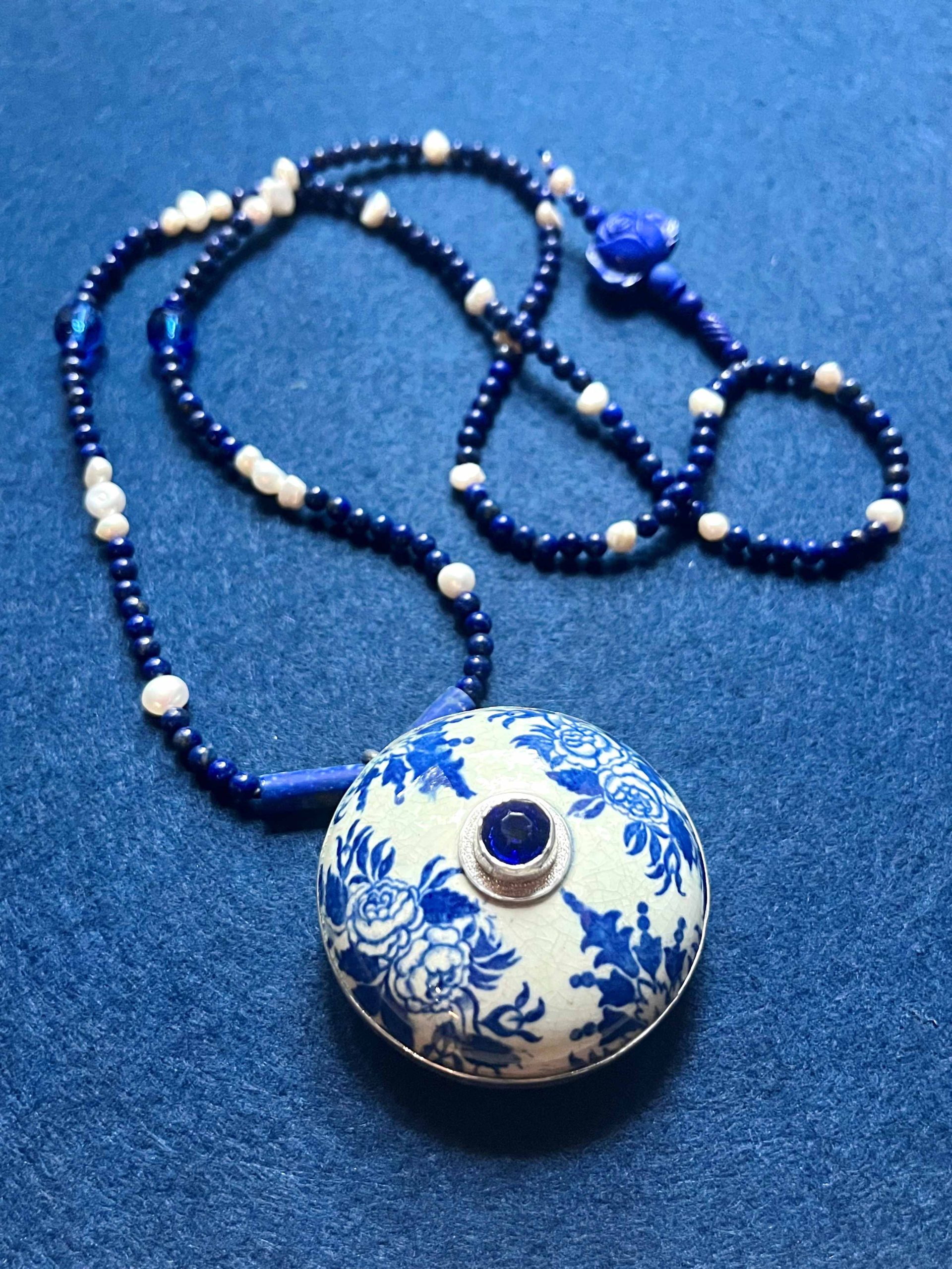 Collier composé d'un couvercle en faïence à décor bleu et blanc du XVII eme siècle, de perles de lapis lazuli, de perles d'eau douce, d'une pate de verre et un cristal de Bohème bleu dans un serti argent. 