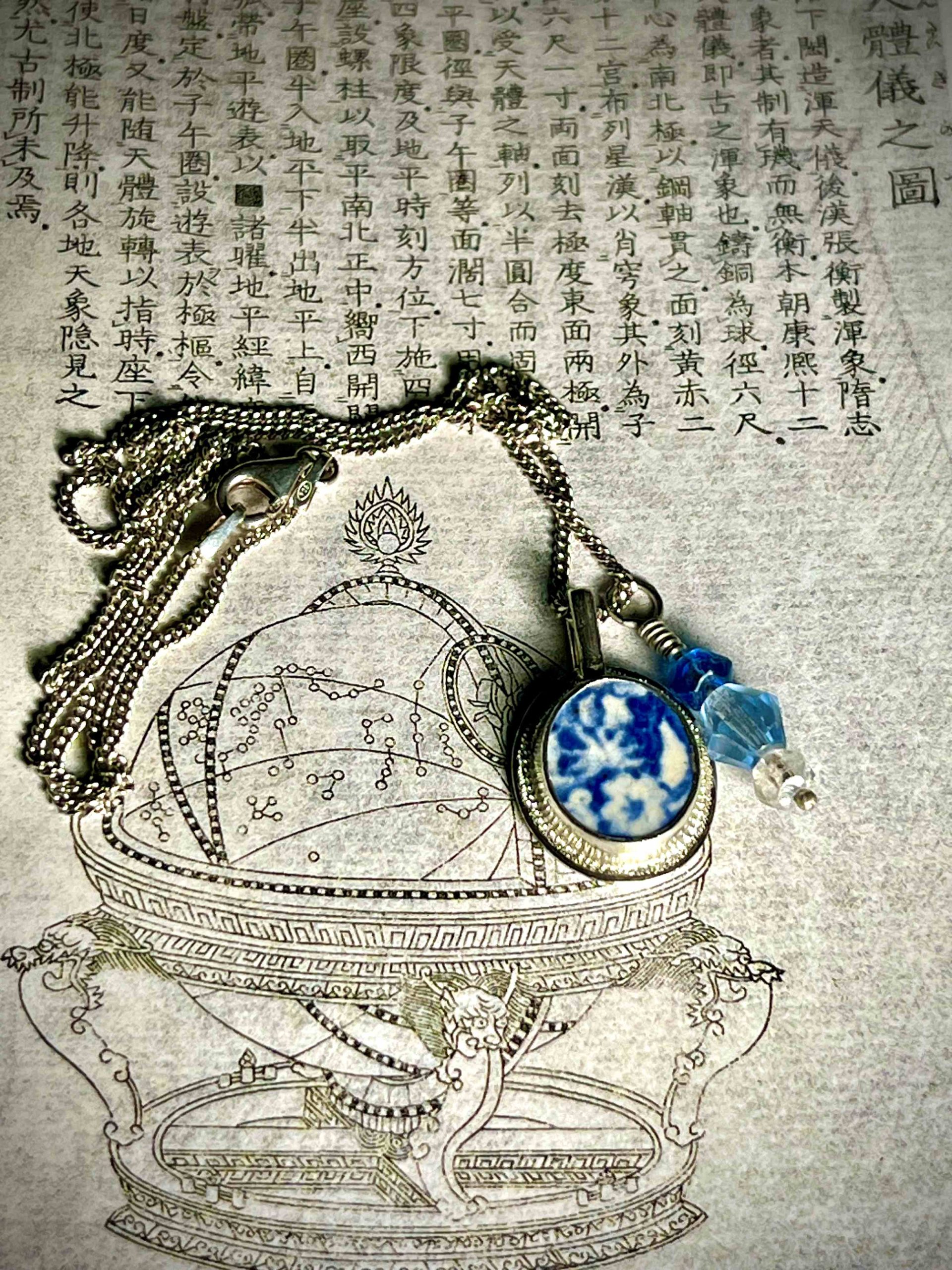 Deux pendentifs en argent sur une chaîne avec en serti un morceau de faïence à décor bleu et blanc et trois perles de cristal de Bohème. 