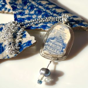 Pendentif en argent avec en serti un morceau de faïence à décor bleu et blanc et trois perles.
